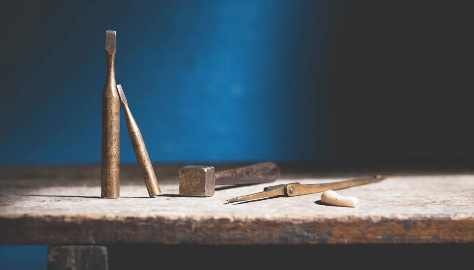 Roman bronze craftsman's tools laid out in a row on a worn bench.